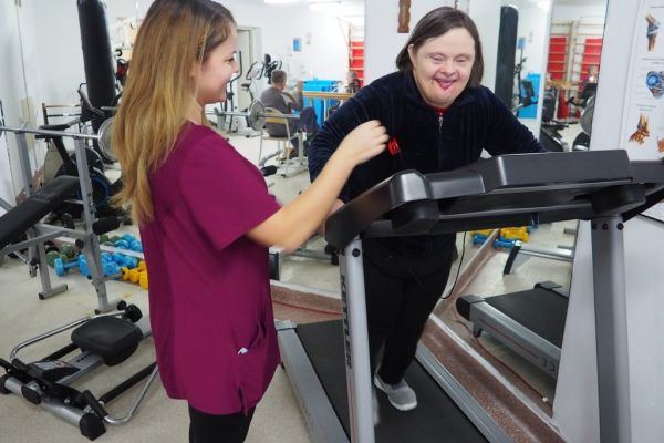 Mieszkanka ćwiczy na sprzęcie do ćwiczeń w sali rehabilitacyjnej.