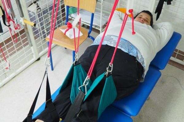 Mieszkanka ćwiczy na sprzęcie do ćwiczeń w sali rehabilitacyjnej.