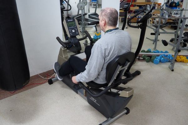 Mieszkaniec ćwiczy na sprzęcie do ćwiczeń w sali rehabilitacyjnej.