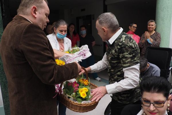 Panowie wręczaja kwiaty paniom z okazji Dnia Kobiet.