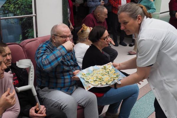 Pracownica dzieli się jajkiem wielkanocnym z Mieszkańcami.