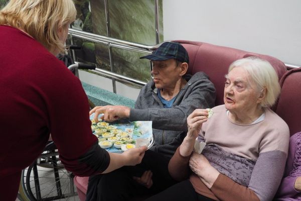 Pracownica dzieli się jajkiem wielkanocnym z Mieszkańcami.