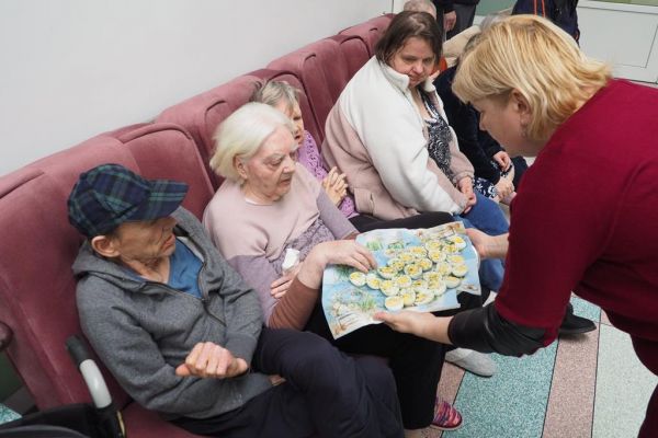 Pracownica dzieli się jajkiem wielkanocnym z Mieszkańcami.