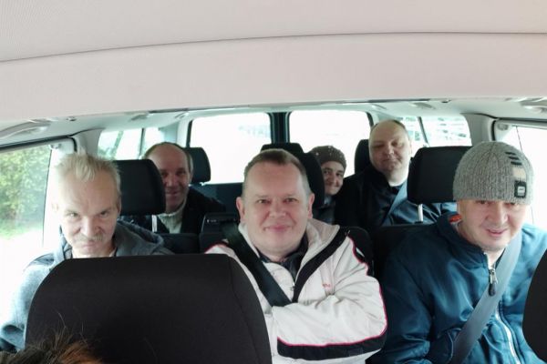 Mieszkańcy siędzą w aucie przed wyjazdem na wycieczkę, mając uśmiechnięte twarze.