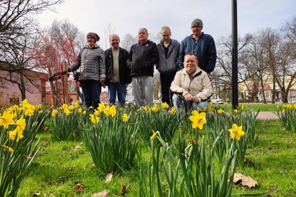 Mieszkańcy pozują do zdjęcia w parku przy kwitnących żonkilach.