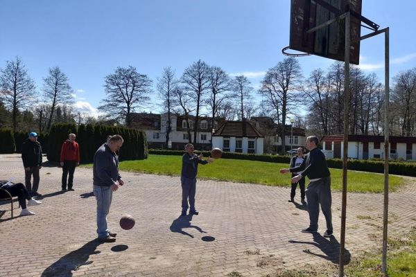 ieszkańcy grają w koszykówkę na terenie domu.