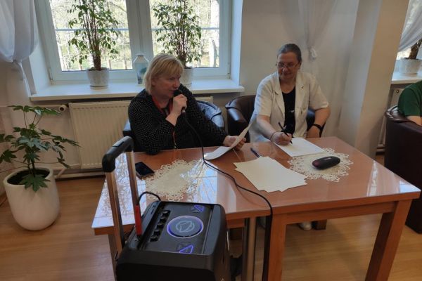 Terapeutki czytaja pytania z quizu Mieszkańcom domu.