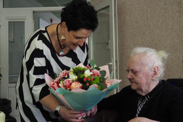 Pani Dyrektor wrecza kwiaty Mieszkance z okazji urodzin.
