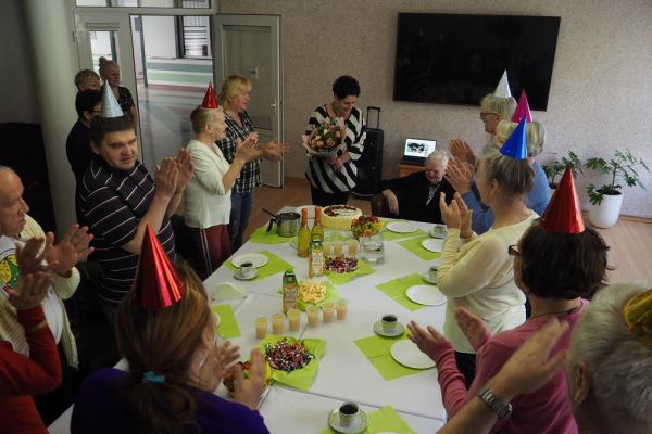 Mieszkańcy na spotkaniu urodzinowym biją brawa jubilatce.