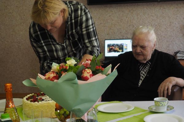 Mieszkanka wraz z terapeutką kroja torta.
