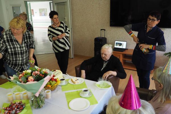 Pani pielęgniarka otwiera piccolo dla siedzącej jubilatki.