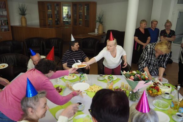 Mieszkanka podaje torta innym podczas urodzin jubilatki Pani Haliny.