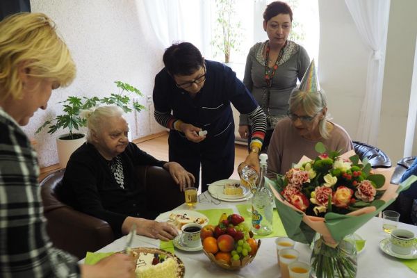 Pani pielęgniarka nalewa piccolo do literatek tuż obok jubilatki.