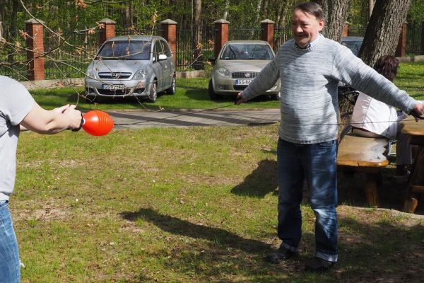 Mieszkaniecy grają w latajaca kulę na świeżym powietrzu podczas grillowania.