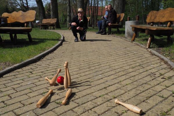 Mieszkaniec gra w kręgle na świeżym powietrzu podczas grillowania.