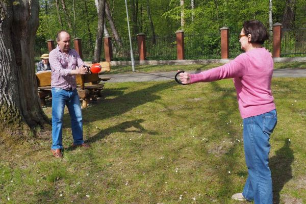 Mieszkaniecy grają w latajaca kulę na świeżym powietrzu podczas grillowania.