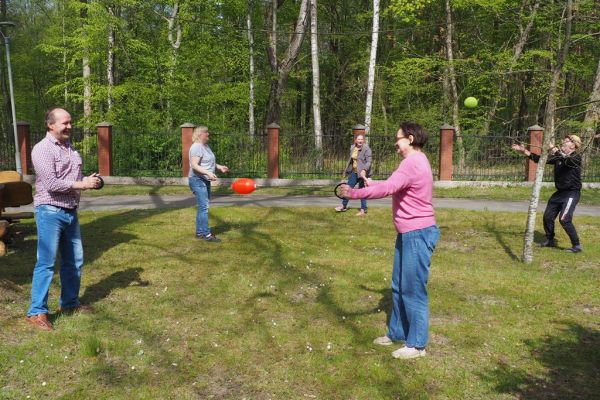 Mieszkaniecy grają w latajaca kulę irzucaja piłką na świeżym powietrzu podczas grillowania.