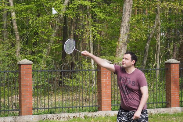 Mieszkaniec gra w badmintona podczas grilla.