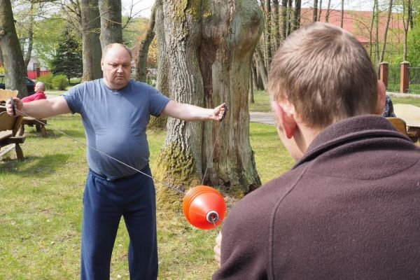 Mieszkaniecy grają w latajaca kulę na świeżym powietrzu podczas grillowania.