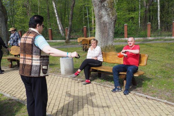 Mieszkaniecy grają w latajaca kulę na świeżym powietrzu podczas grillowania.