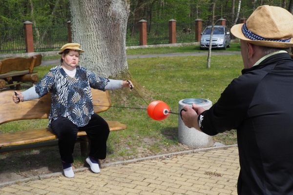 Mieszkaniecy grają w latajaca kulę na świeżym powietrzu podczas grillowania.