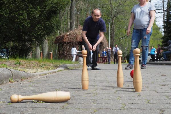Mieszkaniec gra w kręgle na świeżym powietrzu podczas grillowania.