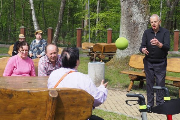 Mieszkańcy rzucają do siebie piłką na świeżym powietrzu podczas grillowania.