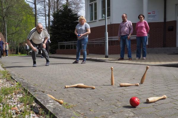 Mieszkaniec gra w kręgle na świeżym powietrzu podczas grillowania.