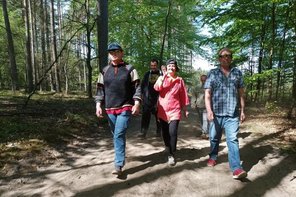 Mieszkańcy spaceruja przez las.