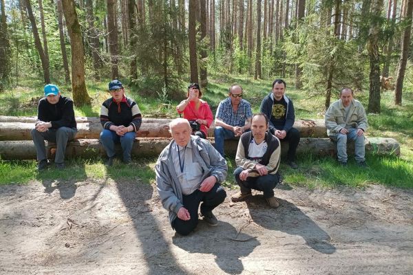 Mieszkańcy odpoczywają w lesie na kłodzie drzewa.