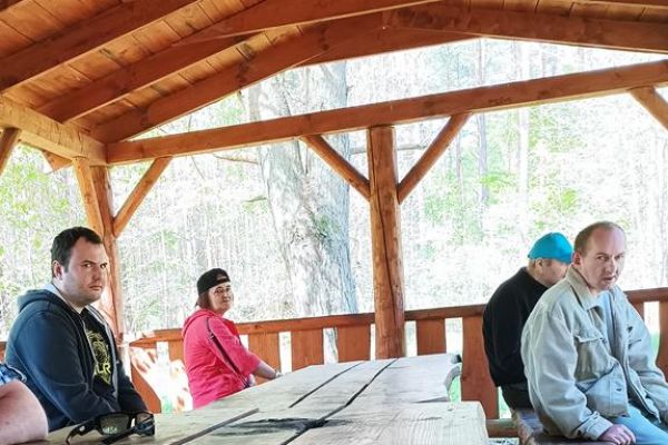 Mieszkańcy odpoczywaja w lesie w wiacie leśnej.