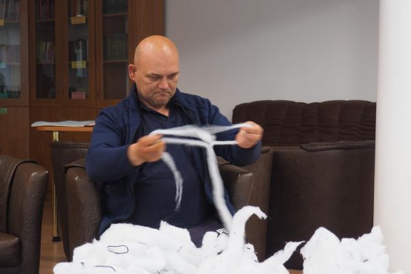 Mieszkaniec drze wypełniacz do poduszek podczas zajęć.
