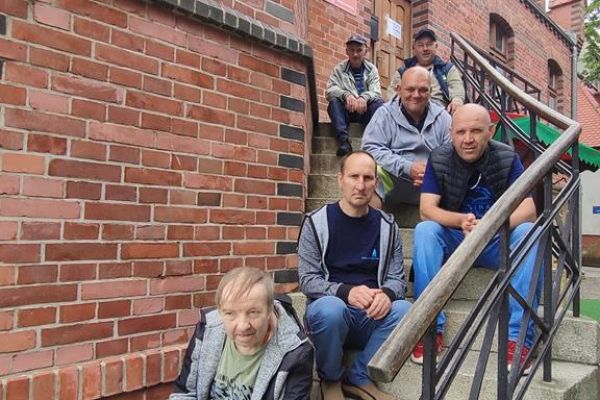 Mieszkańcy siedzą na schodach prowadzących do latarni w Ustce.