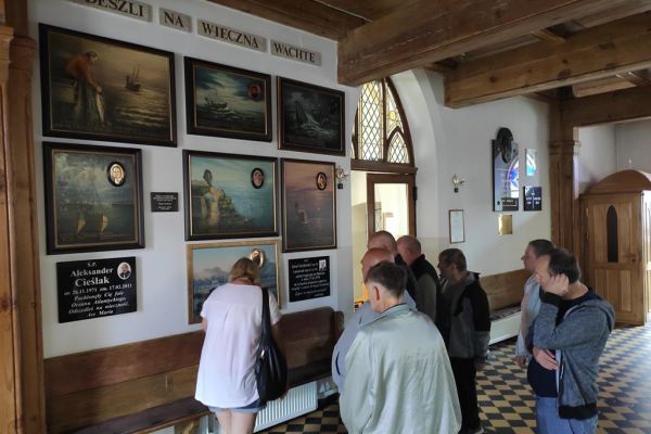 Mieszkańcy oglądaja pamiątkowe obrazy poświęcone pamięci zmarłych marynarzy na morzu w kościele Najświętszego Zawiciela w Ustce.