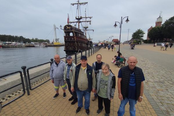 Ujęcie grupy mieszkańców w usteckim porcie na tle statku wycieczkowego.