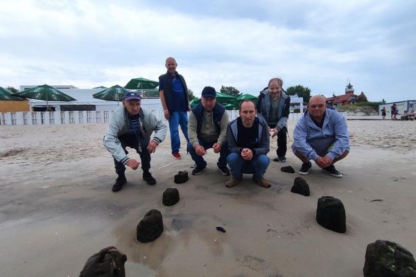 Mieszkańcy pozują w pozycji kucającej na plaży w Ustce.