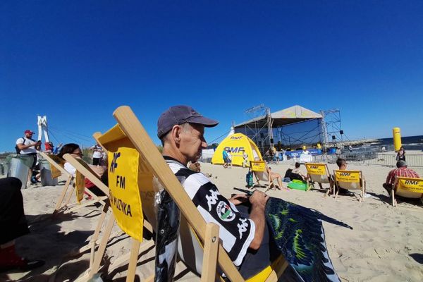 Mieszkaniec siedzi na leżaku na plaży w Ustce.