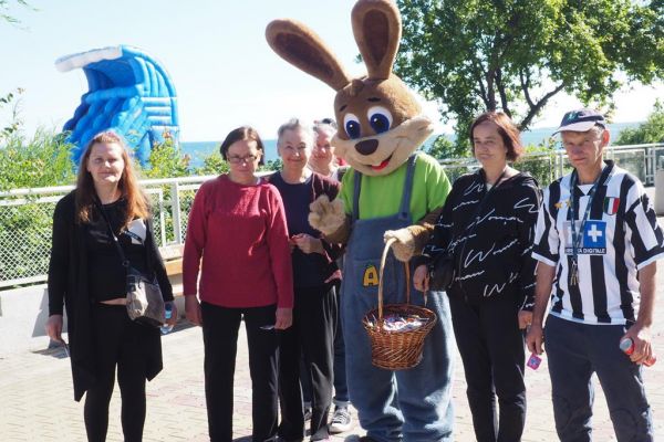 Mieszkańcy pozują do zdjęcia z dużą maskotką zająca na promenadzie w Ustce.