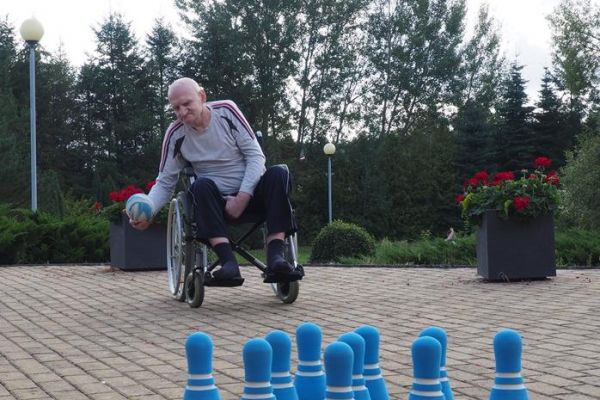 Mieszkaniec rzuca piłką w kręgle.