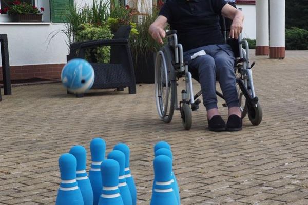 Mieszkaniec rzuca piłką w kręgle.