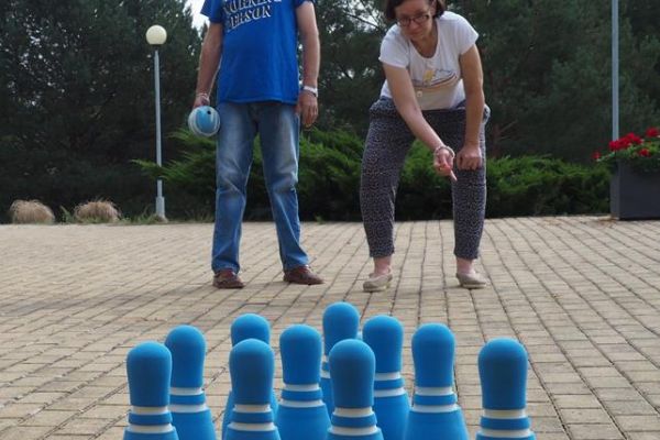 Mieszkańcy rzucają piłką w kręgle.