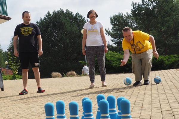 Mieszkańcy rzucają piłką w kręgle.