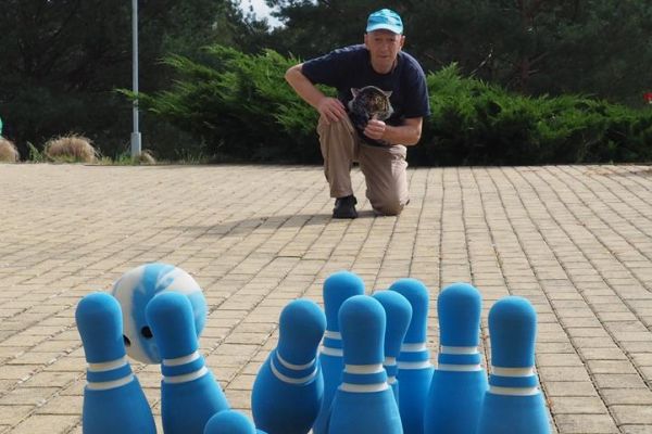 Mieszkaniec rzuca piłką w kręgle.