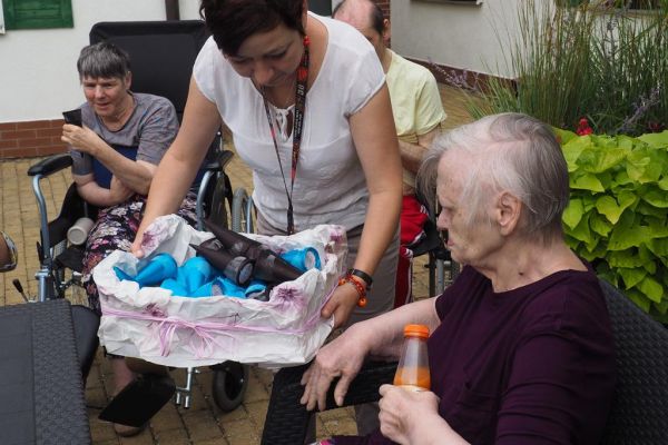 Mieszkańcy częstują się rozdawanymi lodami i je spożywają w upalny dzień siedząc na tarasie Domu.