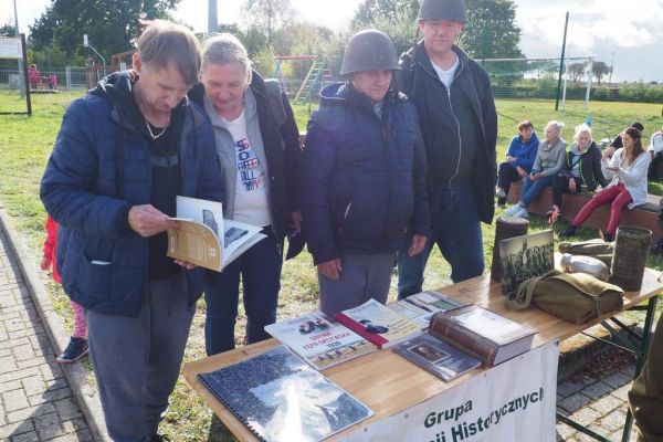 Uczestnicy pikniku oglądaja książki historyczne.