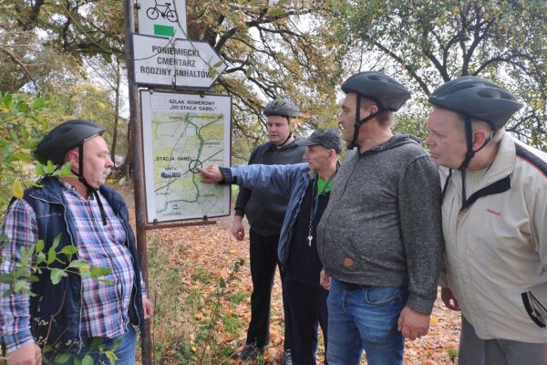 Mieszkańcy czytają tablice informacyjne w lesie.