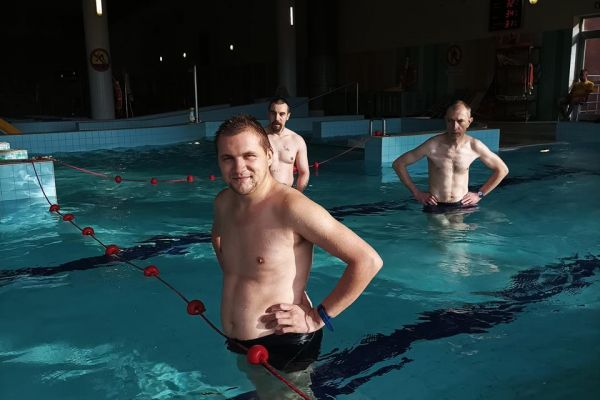 Troje mieszkańców stoi w basenie.