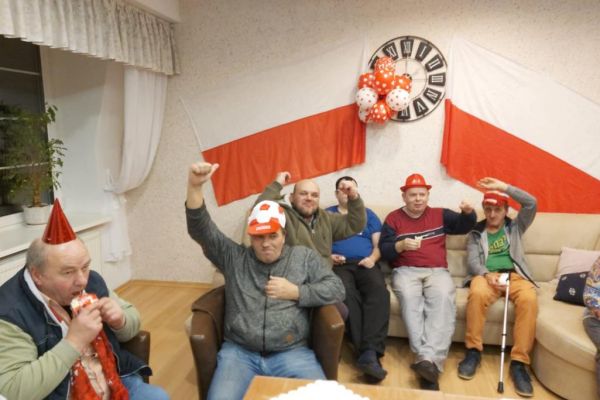 Mieszkańcy kibicują oglądając mecz polskiej drużyny piłkarskiej.