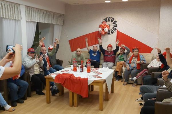 Mieszkańcy kibicują oglądając mecz polskiej drużyny piłkarskiej.
