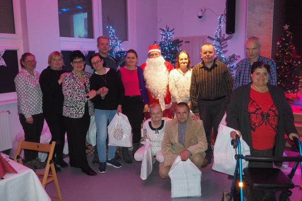 Zbiorowe zdjęcie mieszkańców z mikołajem i pania dyrektor dps.